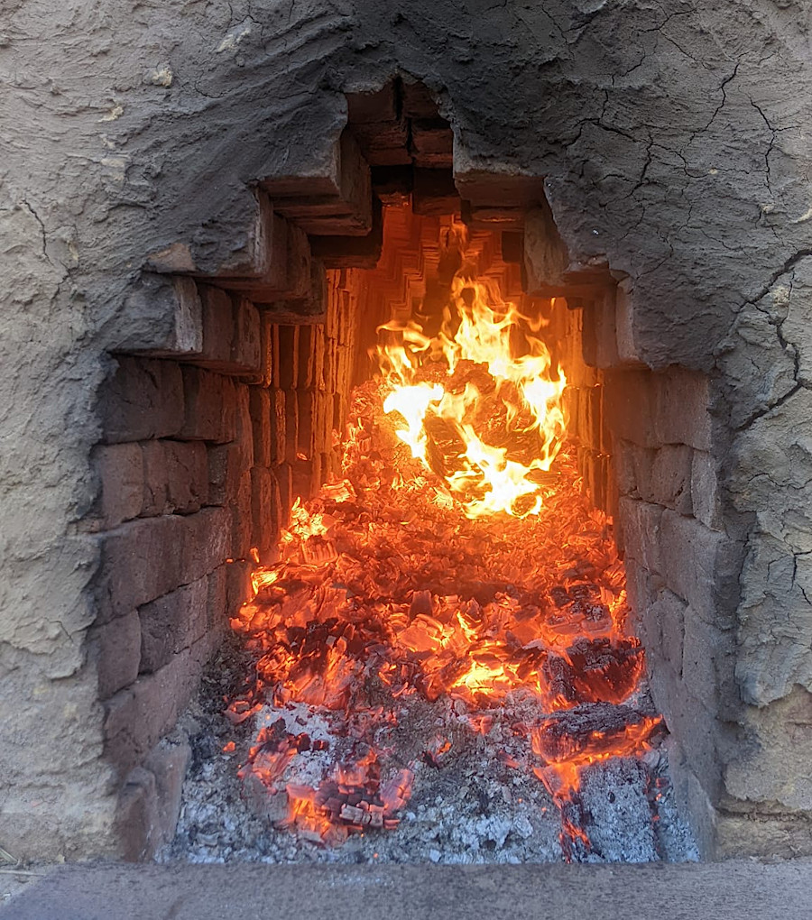 firewood shoved inside the tunnels heats the bricks stacked within the kiln