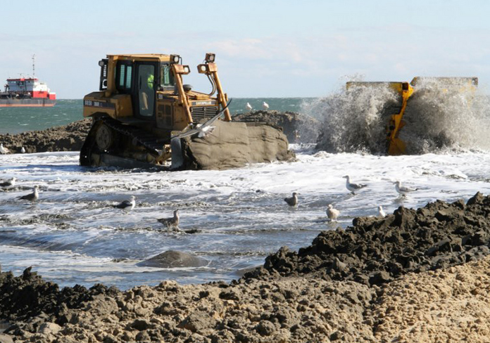 sand pumped onshore from a dredge via pipeline is spread by bulldozer to reshape Virginia Beach