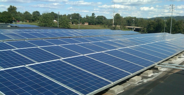 rooftop photovoltaic panels, such as these on Charlottesville High School, replace electricity from central power plants with locally-generated supplies
