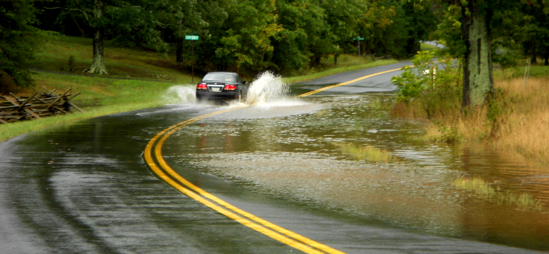 floodwaters on street, washing pollution (oil, worn tire particles, metal filings from brake pads) into local stream
