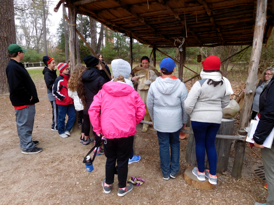 interpreters representing Native Americans within Powhatan's paramount chiefdom interact with visitors at Jamestown Settlement before they reach the recreated fort and replica ships