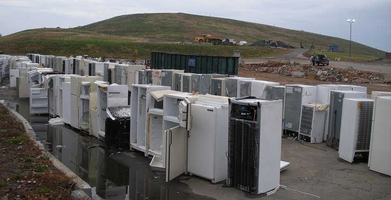 white goods appliances lined up for metal recycling at Prince William County landfill, with closed cell covered by clay cap in background